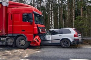 A red truck and a silver SUV are involved in a front-end collision on a road with trees in the background.