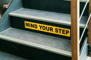 Staircase with a yellow 'Mind Your Step' warning sign on the riser.