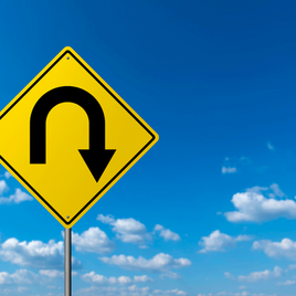 A yellow traffic sign with a black U-turn arrow, set against a blue sky with scattered clouds.
