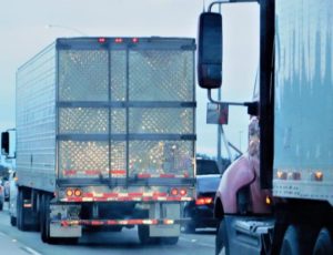 Trucks driving in traffic on a multi-lane highway during the day.