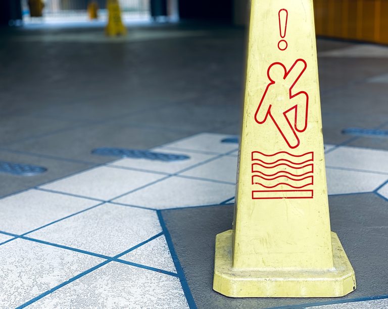 Yellow caution cone with a red icon showing a person slipping and an exclamation point, indicating a wet or slippery floor hazard.